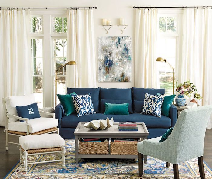 canapé bleu nuit dans un salon blanc aux accents laiton, tapis coloré oriental sur parquet bois foncé