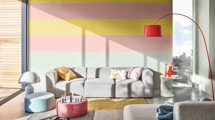 deco appartement contemporain aux murs colorés dans un salon au sol béton aménagé avec meubles en tissu gris
