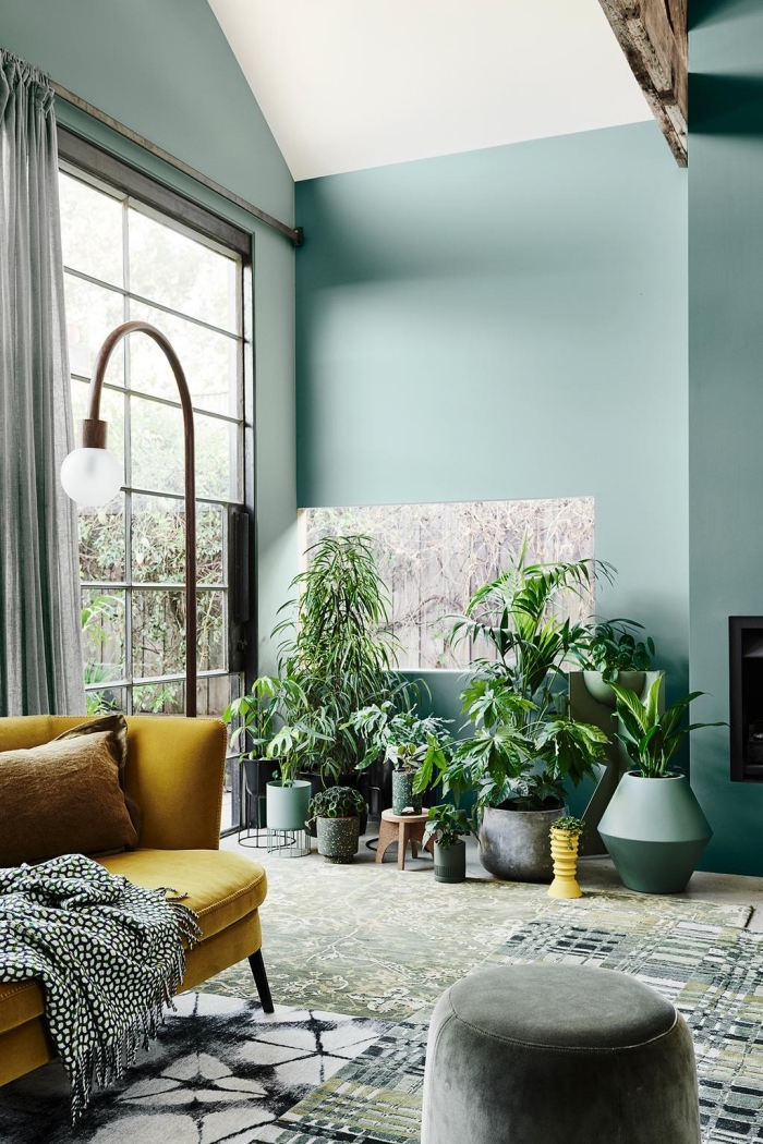 design salon aux murs vert d'eau et plafond blanc décoré de style jungalow aux accents gris et un canapé tendance 2020
