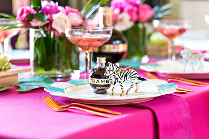 deco de fete tropicale, idee centre de table fleurs rose et fuchsia, nappe couleur fuchsia, marque place anniversaire zebre figurine