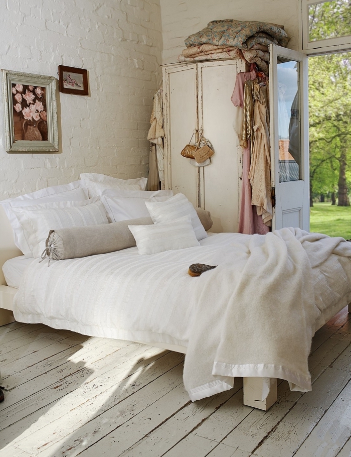 design intérieur style campagne dans une pièce aux murs blancs avec parquet bois blanc aménagé avec grand lit cozy