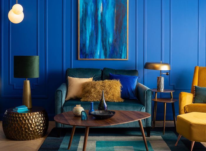 couleur tendance 2020 peinture, murs couleur bleu nuit et canapé bleu petrole, fauteuil jaune, parquet bois clair, tapis vert, bleu et beige