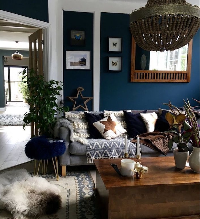 lustre elegant dans un salon bleu nuit avec canapé gris, coussins decoratifs bleu, blanc et marron, plaid gris, table basse bois