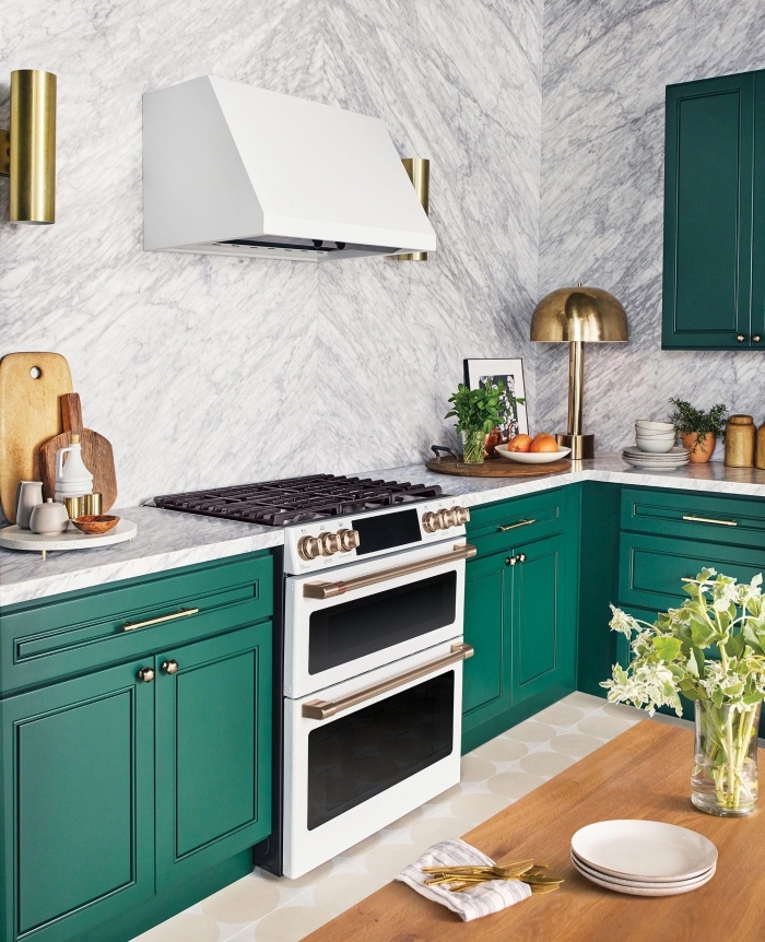 modèle de cuisine contemporaine aux murs à effet marbre blanc aménagée avec armoires de nuance verte et accents dorés