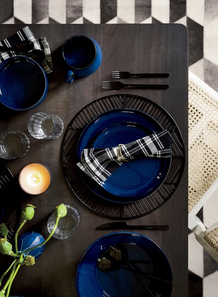 exemple comment décorer une table festive de style moderne avec couverts en noir et assiettes en bleu marine, pliage serviette tissue