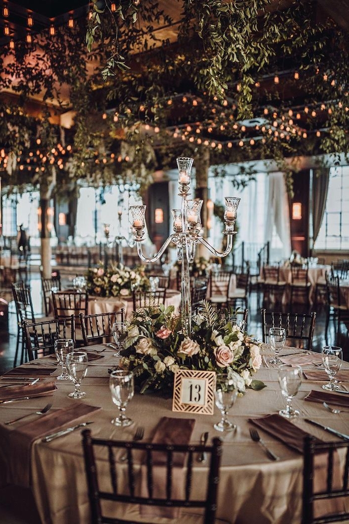 centre de table mariage en végétation verte et fleurs rose, plafond végétalisée et illuminée par guirlandes lumineuses, bougeoirs en verre, idee deco mariage romantique