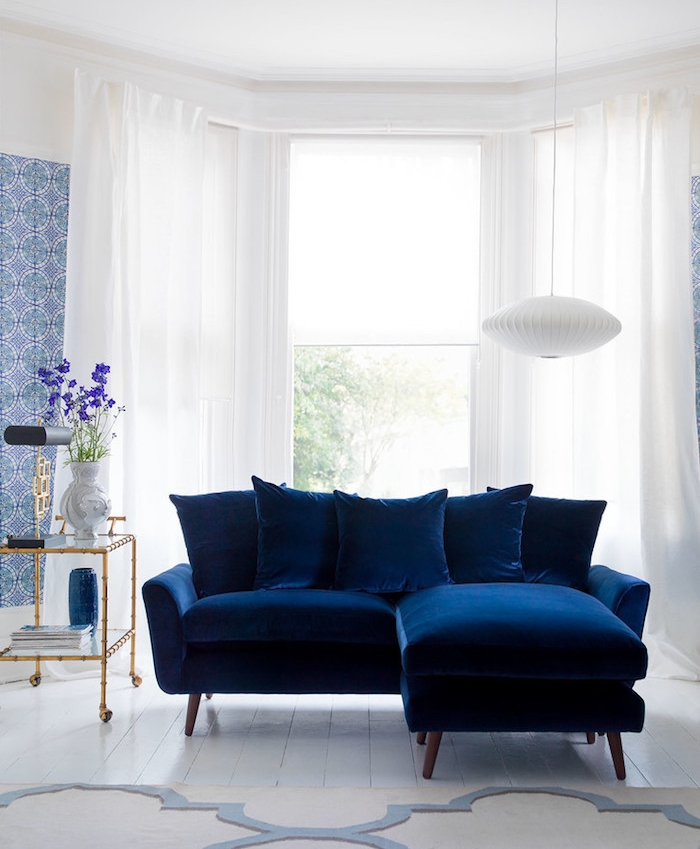 modele de canapé bleu nuit dans un salon blanc avec décoration murale lé de papier peint blanc et bleu imprimé floral