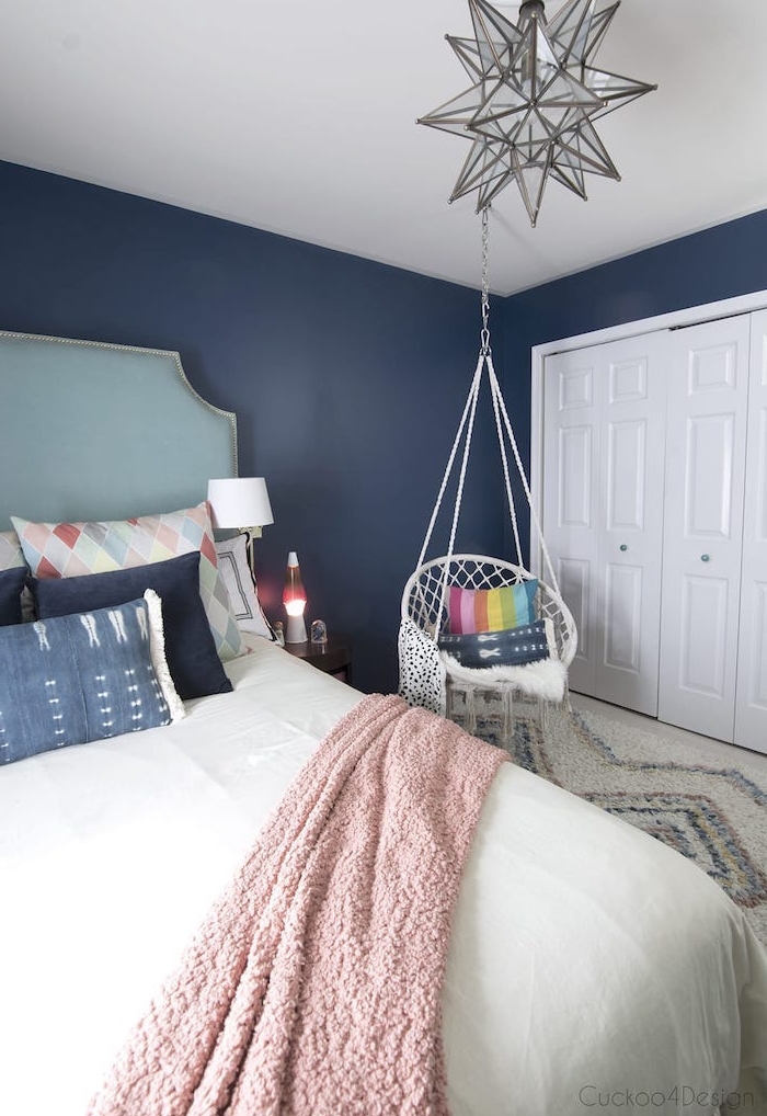 couleur peinture chambre bleu foncé, balançoire suspendu, coussins décoratifs colorés, plaid rose, tapis gris et blanc, suspension étoile