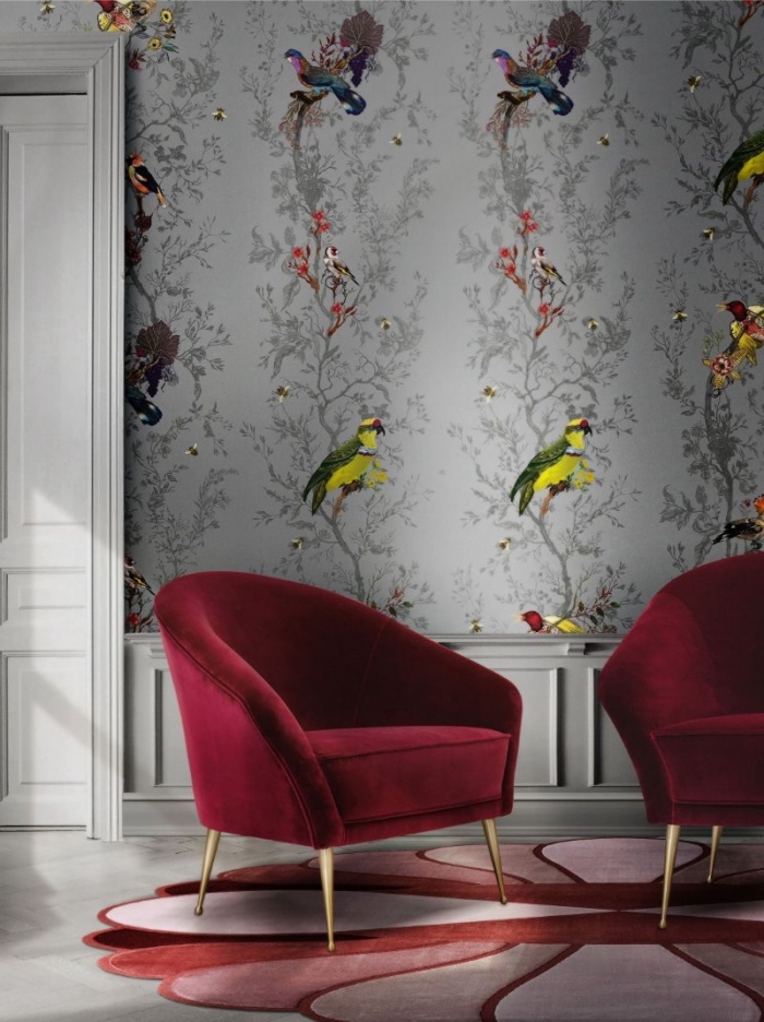 deco tendance 2020 dans un salon aux murs en papier peint gris à motifs oiseaux colorés aménagé avec meubles en velours rouge