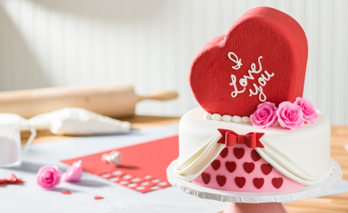 modèle de gâteau romantique au fondant blanc décoré avec figurines en fondant rouge sous forme de petits coeurs