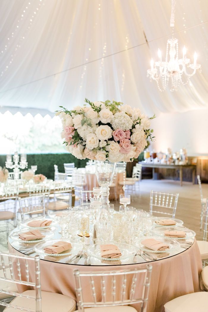 décoration mariage table en nappe et serviettes rose pâle avec centre deco bouquet de fleurs enorme, ciel drapé, chaises transparentes