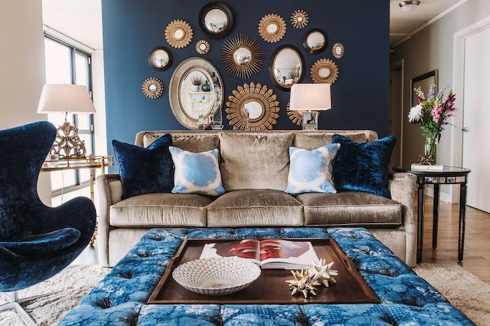 mur d accent bleu foncé pantone bleu avec deco miroirs, canapé gris, coussins blanc et bleu, table basse bleu avec centre de bois, fauteuil oeuf bleu