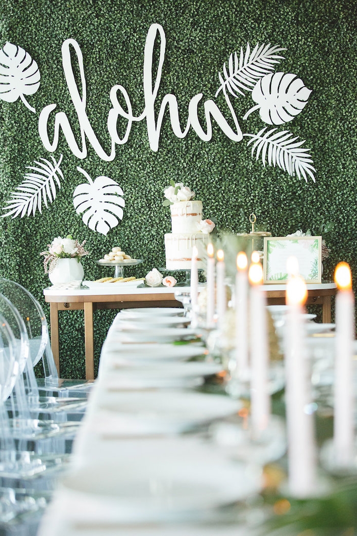 i;dee thème mariage hawaii avec mur décorée de végétation verte avec mot aloha, candy bar mariage blanc, centre de table mariage feuillages et bougies blanches