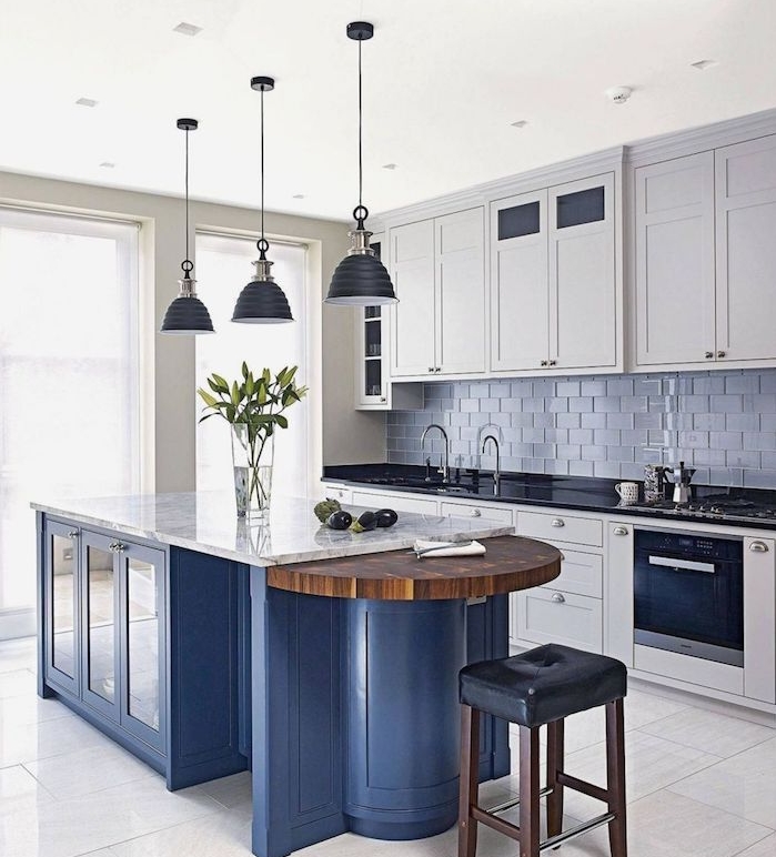 ilot central bleu dans une cuisine blanche et grise avec meubles cuisine blancs, carrelage credence gris
