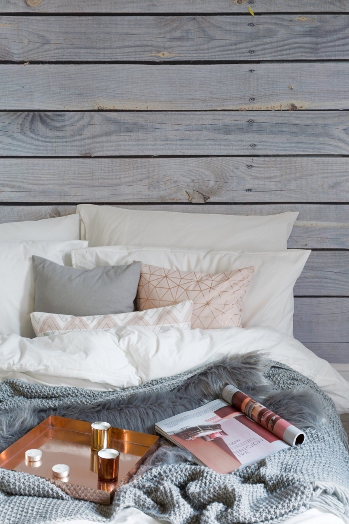 exemple de lit cocooning décoré de coussins et de plaids en couleurs neutres dans une chambre aux murs à effet planches de bois
