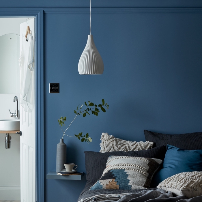 idée de deco chambre parentale aux murs bleu foncé avec un lit cocooning couvert de coussins en nuances de bleu