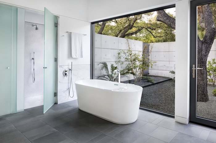 Baignoire ovale dans la salle de bain grand espace qui donne au jardin, choisir le marbre blanc
