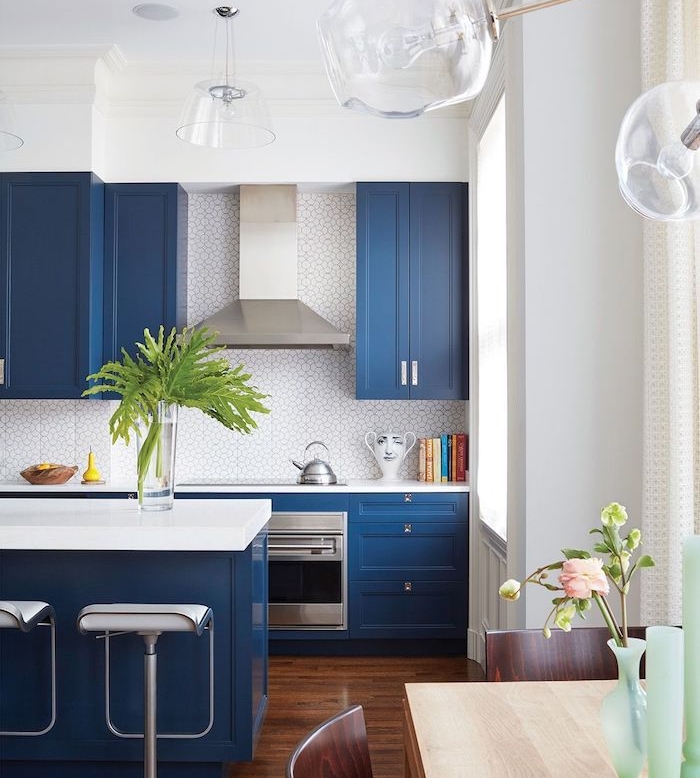 ilot central, meuble cuisine couleur bleu foncé, carrelage credence blanc, plan de travail blanc, parquet bois foncé