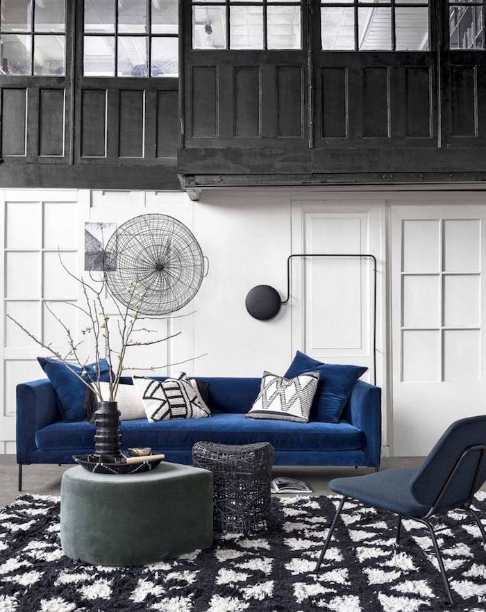 salon noir et blanc avec accent bleu canapé bleu foncé, tapis noir et blanc, murs blancs