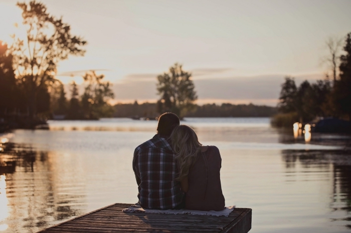 photo de couple amoureux qui observe le coucher de soleil romantique au bord d'un lac, idée rendez-vous dans un endroit romantique