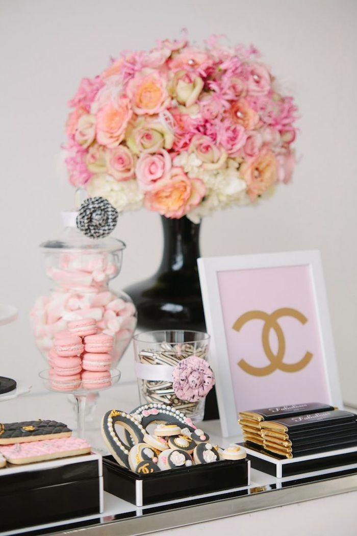 bouquet de fleurs dans un vase noir, dragées, macarons et biscuits noir et rose, chocolats paquet noir et or