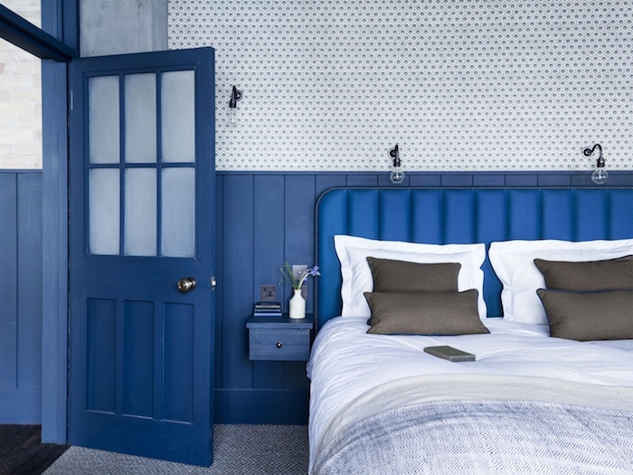 murs et porte bleus, linge de lit gris et blanc sur lit avec tete de lit bleue, tapis gris et blanc, deco vintage couleur peinture salon