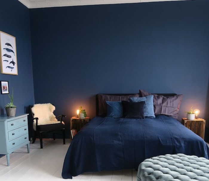 plafond et sol blanc et murs bleu nuit, coussins et oreillers bleu et marron, table de nuit en cagette de bois, idee deco chambre adulte homme