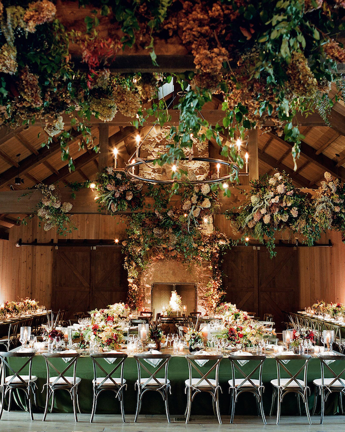 mariage dans vieilles granges boisées avec décoration plafond florale, cheminée mariage et tables en vert fleuries