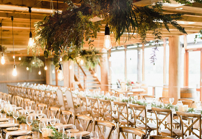 suspensions ampoules industrielles et déco florale de feuillages au dessus de table et chaises de bois et petite deco aux feuillages verts