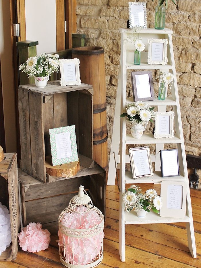 echelle deco originale avec échelle blanche décoré de plan de table mariage petites listes encadrées, cagettes deco vintage