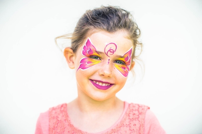 modèle de maquillage fille à design papillon réalisé à l'aide d'un pochoir et des peintures pour visage rose et jaune