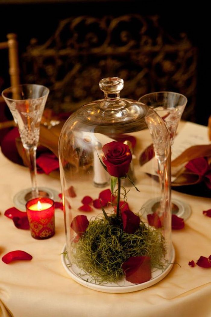 Table avec nappe blanche et cloche avec rose rouge, bougie et petales décoration de saint valentin, préparer une surprise pour ma copine