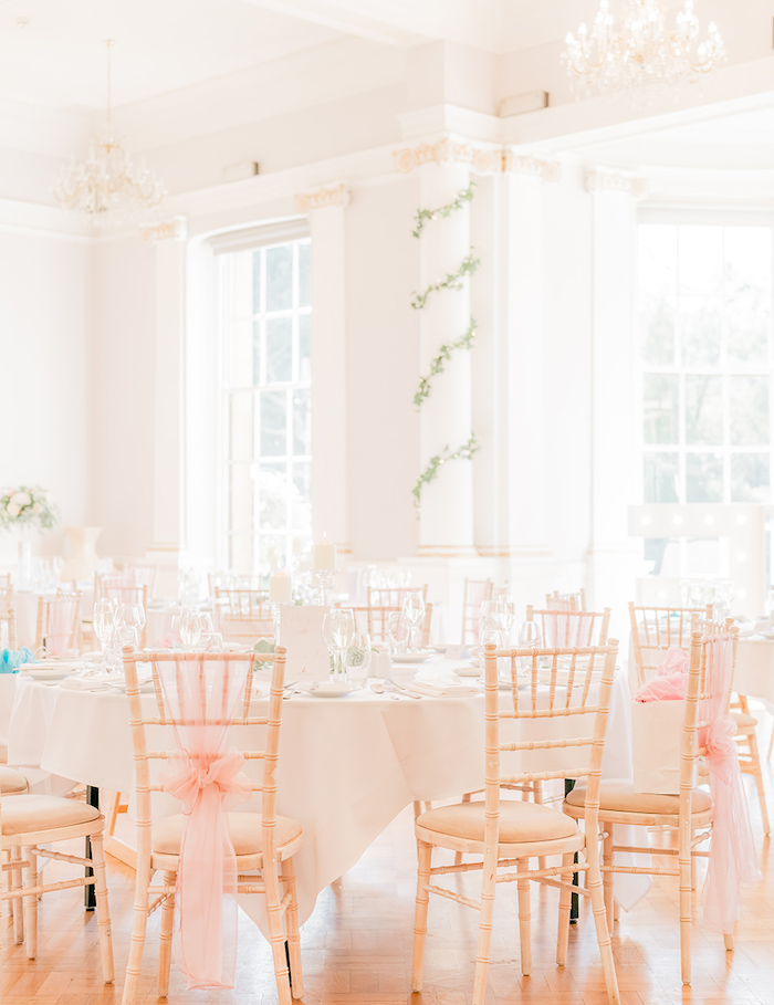 déco chaise de mariage en rubans rose, tables décorés de blanc avec verres transparentes, deco colonne de guirlande feuillage