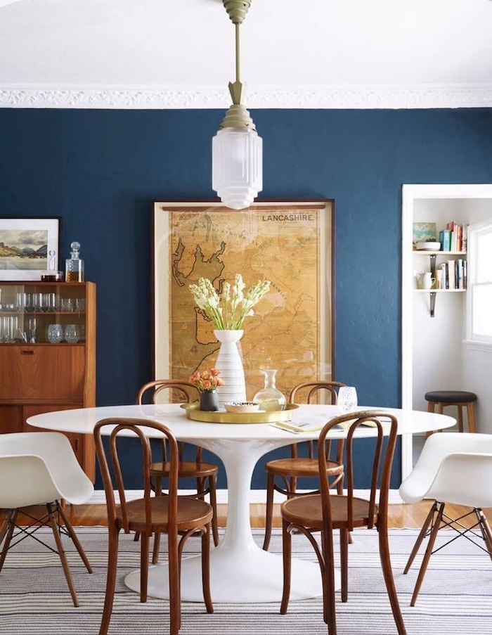 table salle à manger blanche entourée de chaises de bois, murs bleus, avec deco mappemonde vintage, vaisselier bois vintage, parquet bois clair