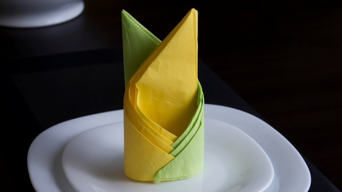 technique de pliage de serviette facile en deux couleurs, déco de table élégante avec assiettes rondes et serviette jaune vert