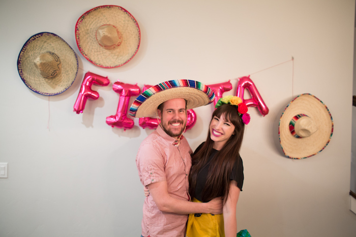 organiser une soirée mexicaine avec deco murale de chapeaux de paille, lettres ballons fiesta, femme et homme qui sourient