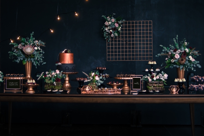 style-theme-anniversaire-30-ans-mur-foncé-grillage-décoratif-fleurs-brins-feuilles-couverts-plateaux-cuivre-lampe-ampoules exemple de décoration anniversaire 30 ans homme ou femme de style contemporain en noir avec accents métallisés et fleurs