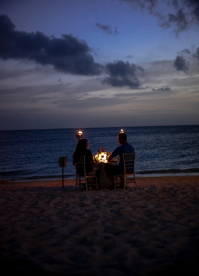 organiser un dîner surprise dans un endroit romantique, couple amoureux assis à table romantique sur la plage