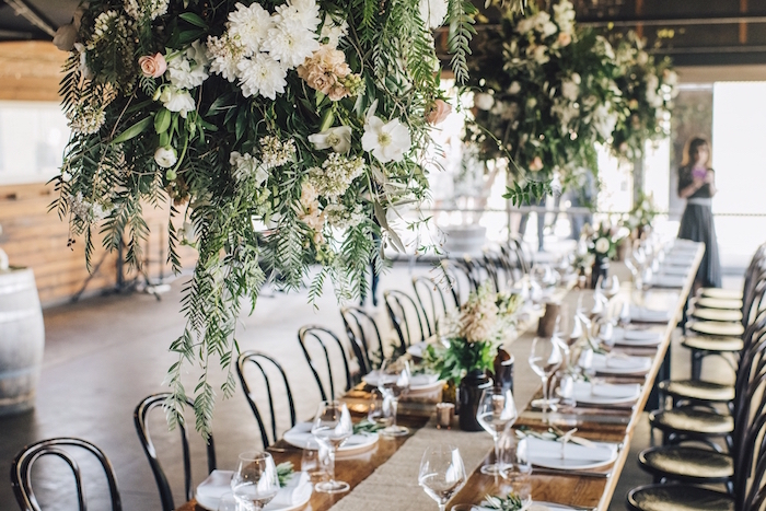 suspension boules végétales aux fleurs au dessus d une table rustique, chemin de table jute, décoration de table mariage campagne chic