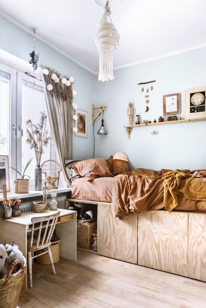 aménagement de petite chambre d'enfant aux murs bleu clair avec meubles en bois et accessoires de style bohème