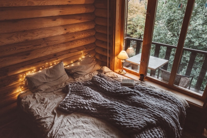 idée déco chambre cozy dans un chalet bois, exemple comment décorer un lit avec gros jeté de lit et guirlande lumineuse