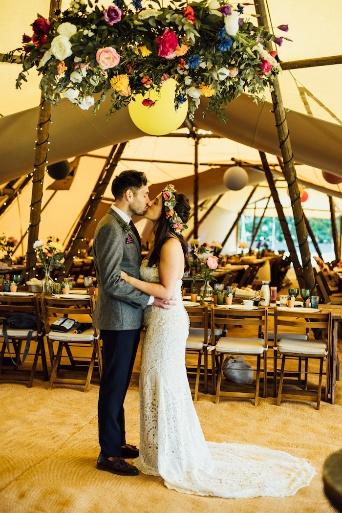 suspension florale géante comme décoration salle de mariage avec tapis fauve, table et chaises bois, tente mariage énorme