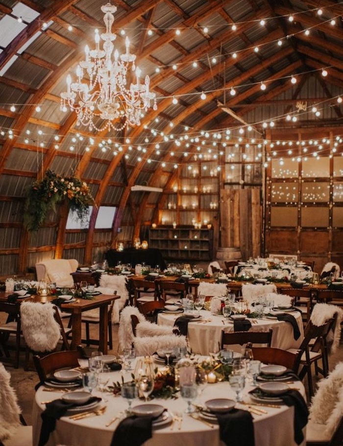 lustre elegant et guirlande lumineuses pour decorer plafond arqué, tables rondes décorées de noir et blanc, centre vegetation et bougies