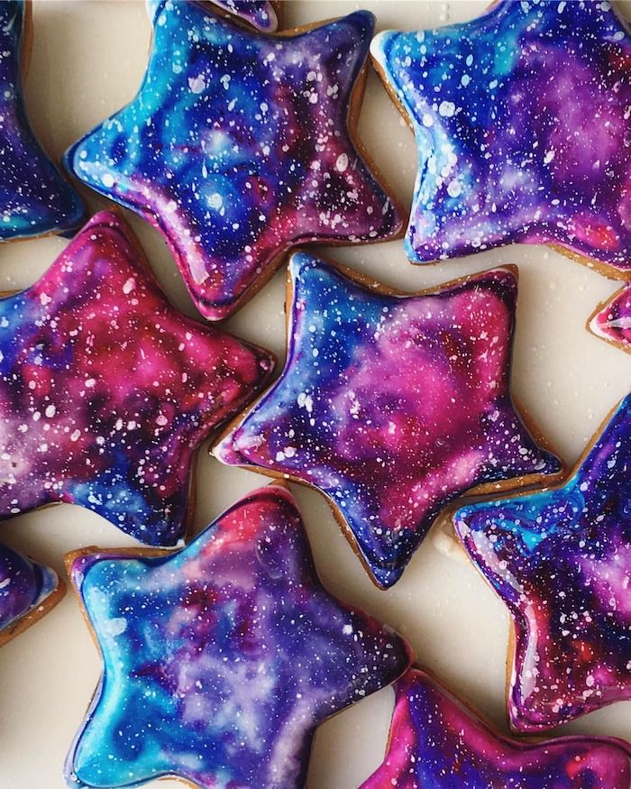 biscuits décorés de glaçage miroir galaxie en rose, bleu nuit, mauve et des touches de blanc pour imiter les étoiles