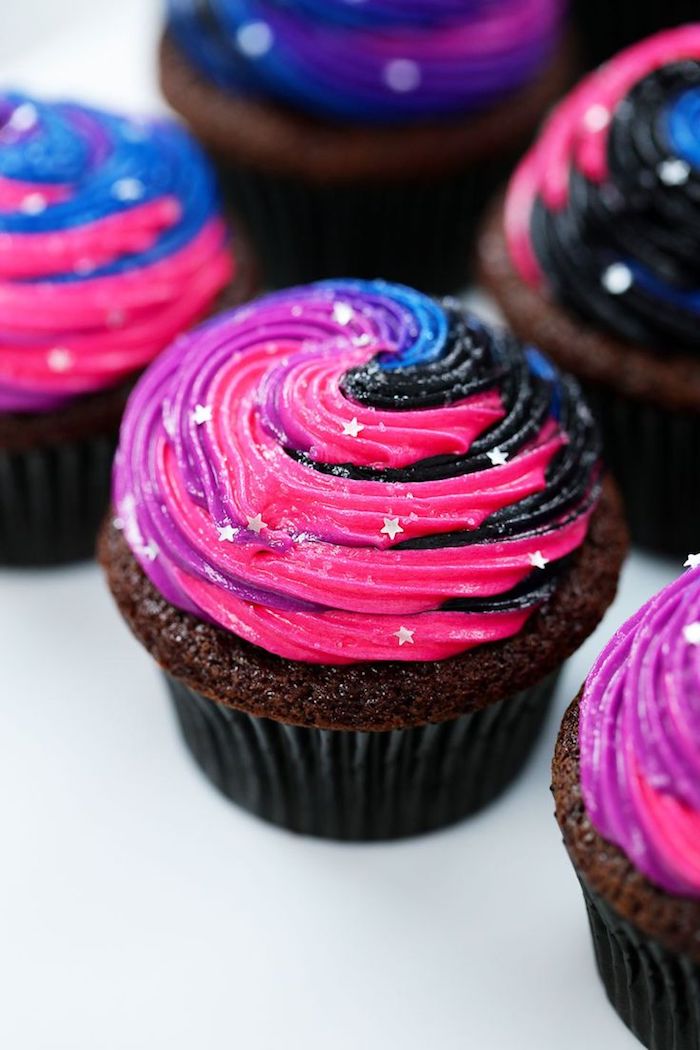cucpakes arc en ciel, motif licorne et galaxie sur cupcake chocolat décoré de glaçage rose, violet, bleu, noir et étoiles comestibles