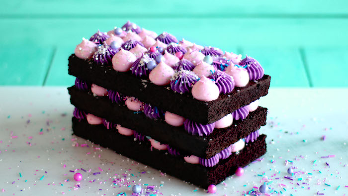 gateau de couches avec genoise au chocolat cacao et creme violet et rose entre les couches, decoration de billes colorées