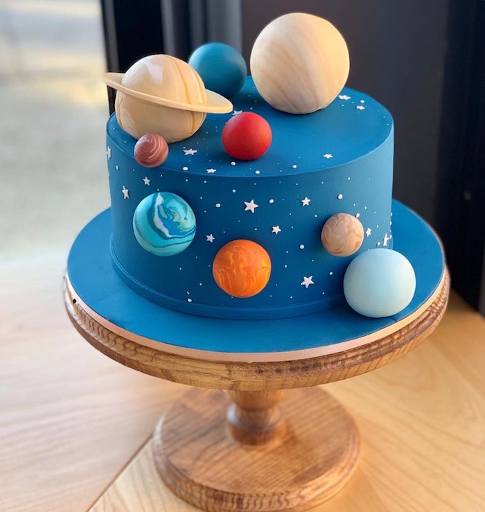 gateau décoré de glacage bleu, planetes systeme solaire cake pop et deco etoiles blanches decoratives