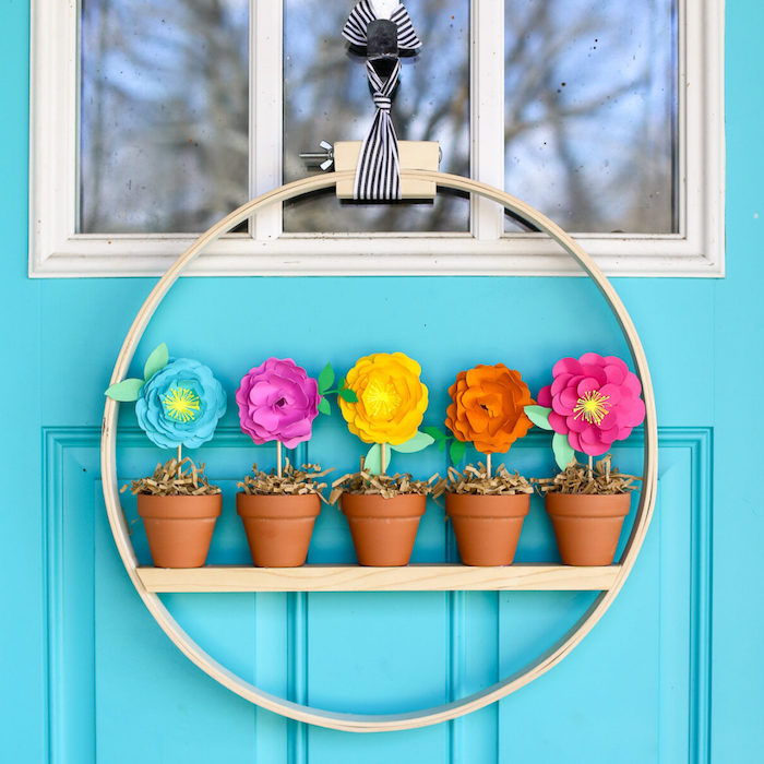 decoration de porte originale, cerceau de bois avec de mini pot de terre avec des fleurs de papier coloré à l interieur