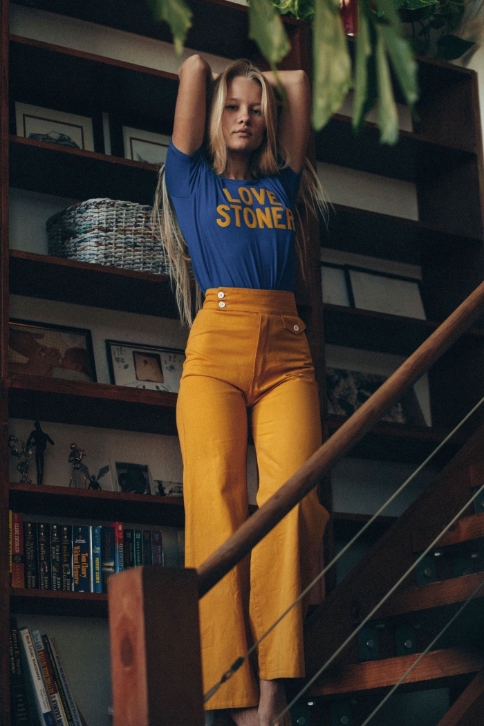 style année 70 pour femme, tenue casual chic en pantalon évasé à taille haute de couleur jaune combiné avec t-shirt bleu
