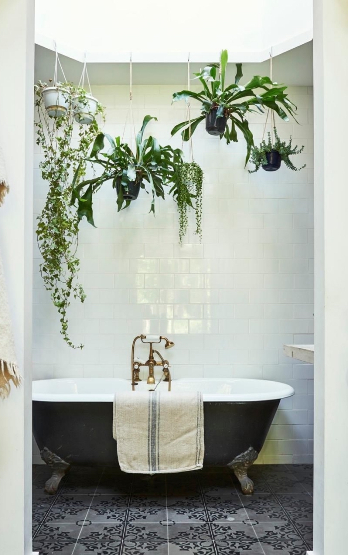 déco salle d'eau d'esprit jungalow avec plante grasse retombante, suspensions florales au-dessus d'une baignoire noir et blanc